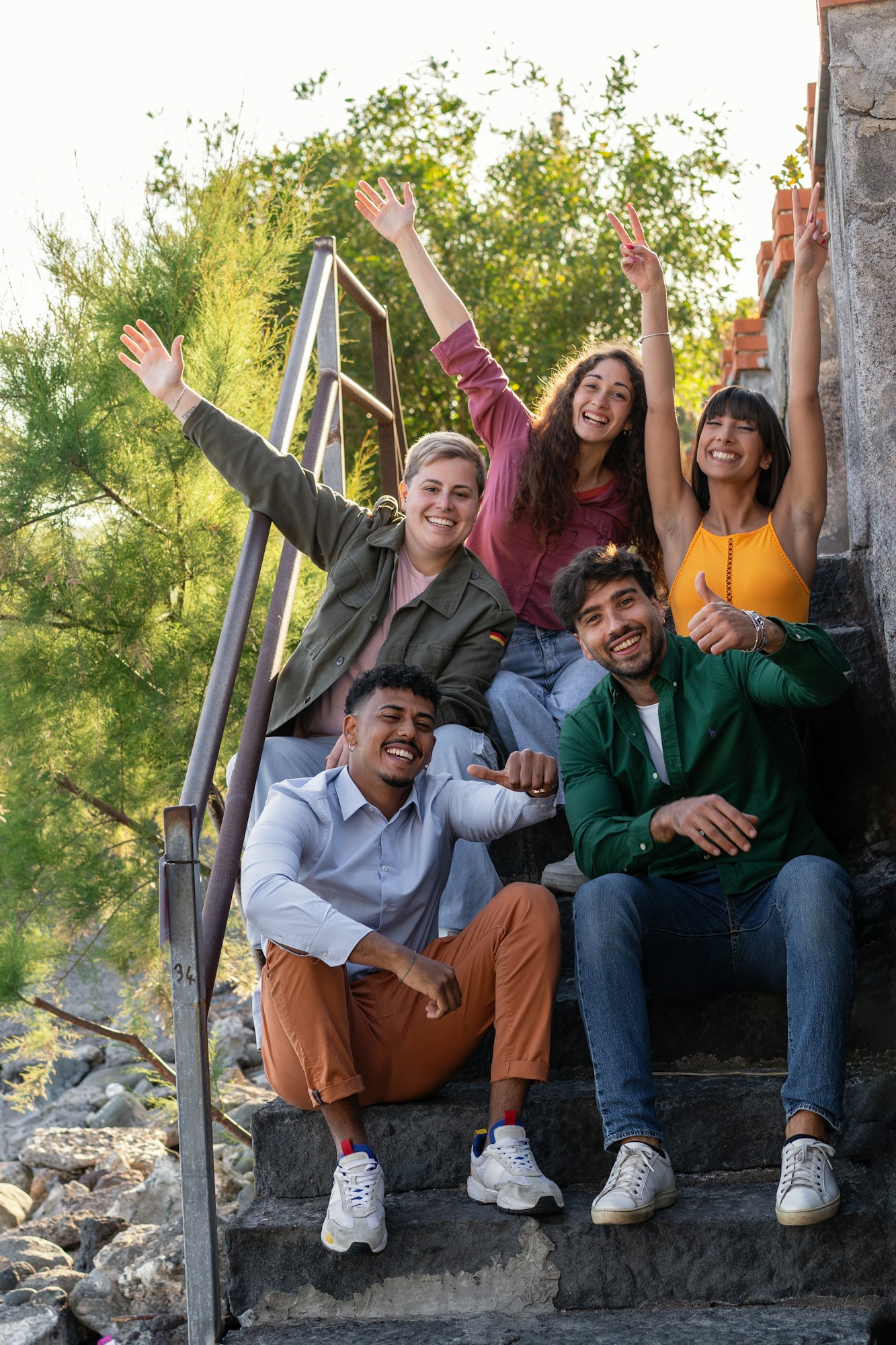 Diverse Group by Sea Posing with Raised Hands